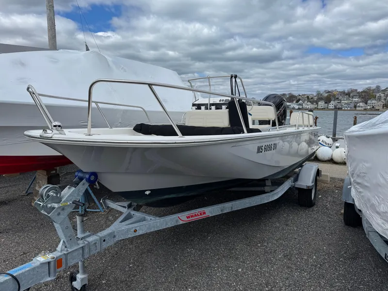 Slide: The Image of 2023 Boston Whaler 170 Montauk boat on trailer, parked near waterfront under cloudy sky. - 1
