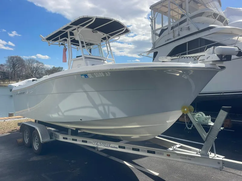 Slide: The Image of 2022 Aquasport 2100 CC boat on trailer, parked near water under a blue sky. - 1