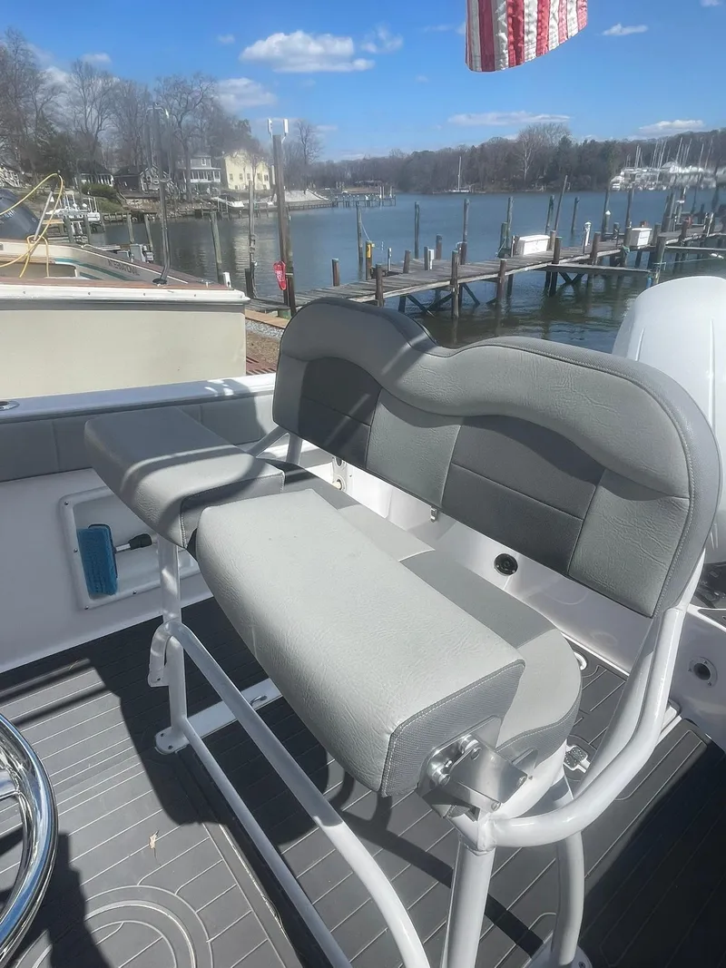 Slide: The Image of 2022 Aquasport 2100 CC boat interior with gray seating, dockside view. - 11