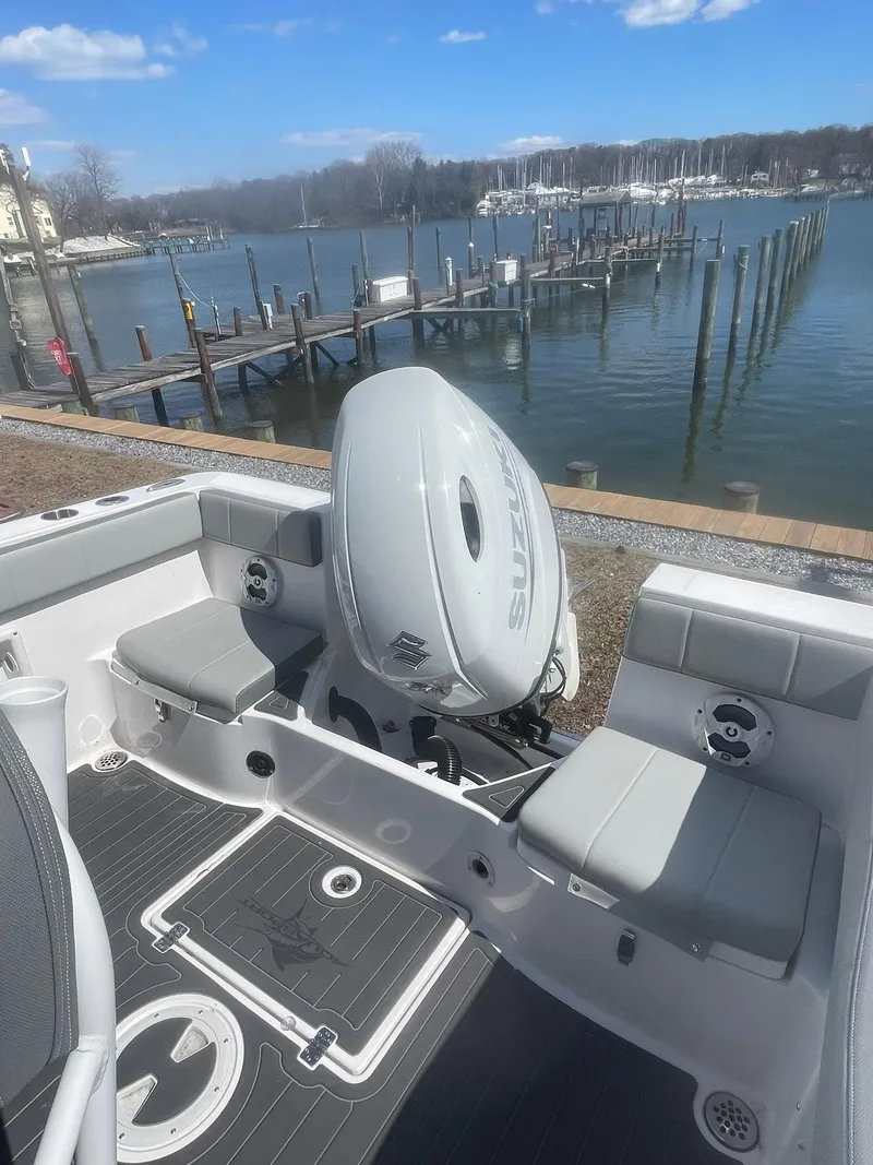 Slide: The Image of 2022 Aquasport 2100 CC boat with outboard motor, docked by a serene waterfront. - 12