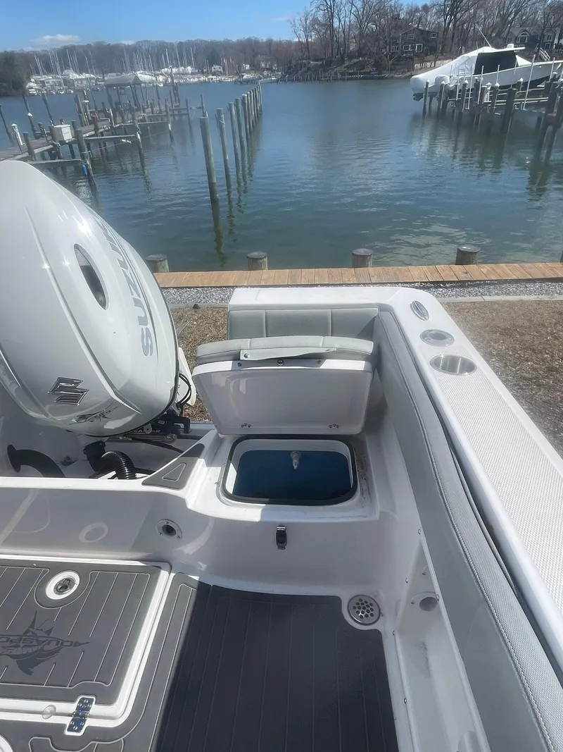 Slide: The Image of 2022 Aquasport 2100 CC boat with open hatch, docked by a serene waterfront. - 13