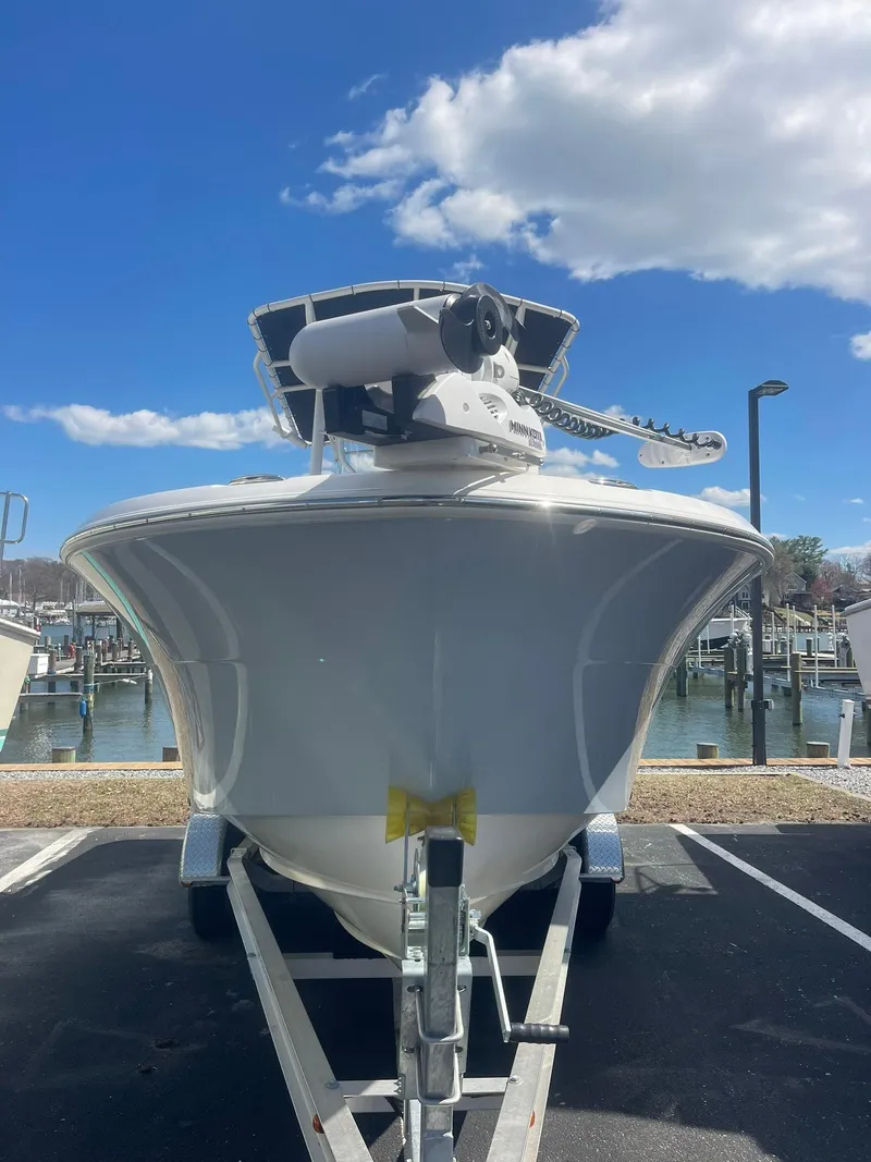 Slide: The Image of 2022 Aquasport 2100 CC boat on trailer, dockside view under blue sky. - 2