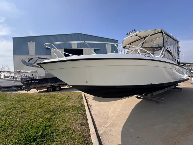 Slide: The Image of 1998 Contender 35 Express Side Console boat on trailer near a large blue warehouse. - 1