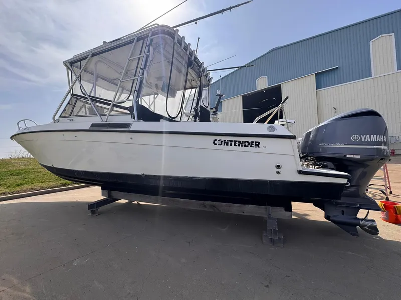 Slide: The Image of 1998 Contender 35 Express Side Console boat with Yamaha outboard, docked near a blue building. - 7