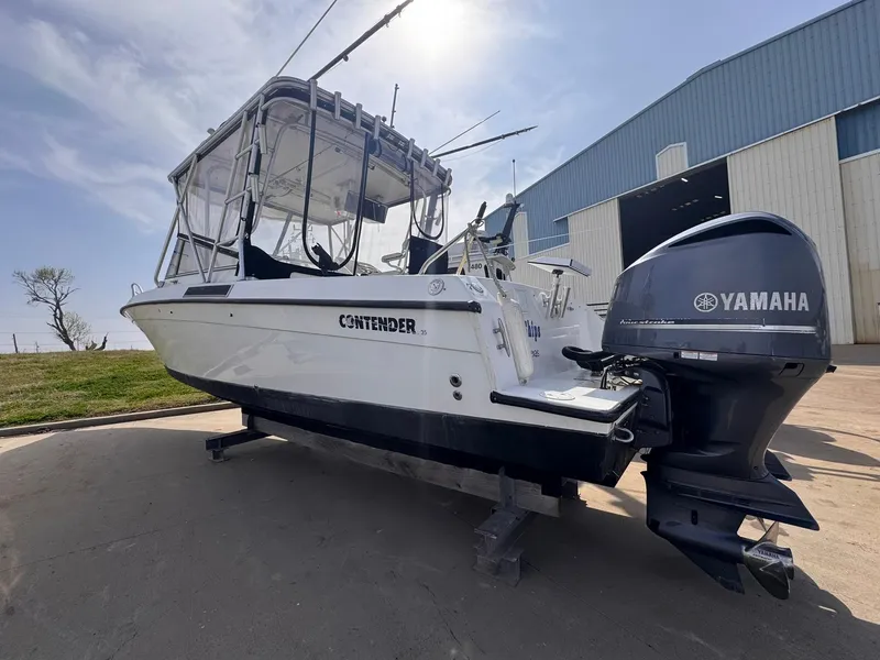 Slide: The Image of 1998 Contender 35 Express Side Console boat with Yamaha outboard, parked near a warehouse. - 9