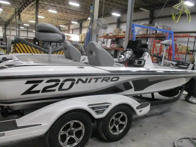 Slide: The Image of 2024 Nitro Z20 boat in a warehouse, featuring sleek design and dual-axle trailer. - 0