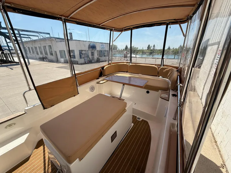 Slide: The Image of 2016 Ranger Tugs R-21 EC boat interior with tan seating and table, docked at marina. - 11