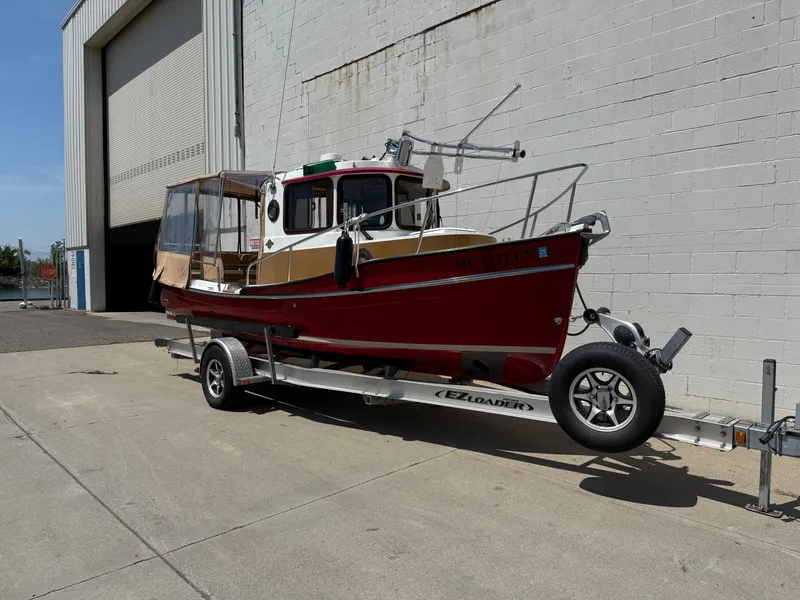Slide: The Image of 2016 Ranger Tugs R-21 EC boat on trailer outside a large garage. - 17