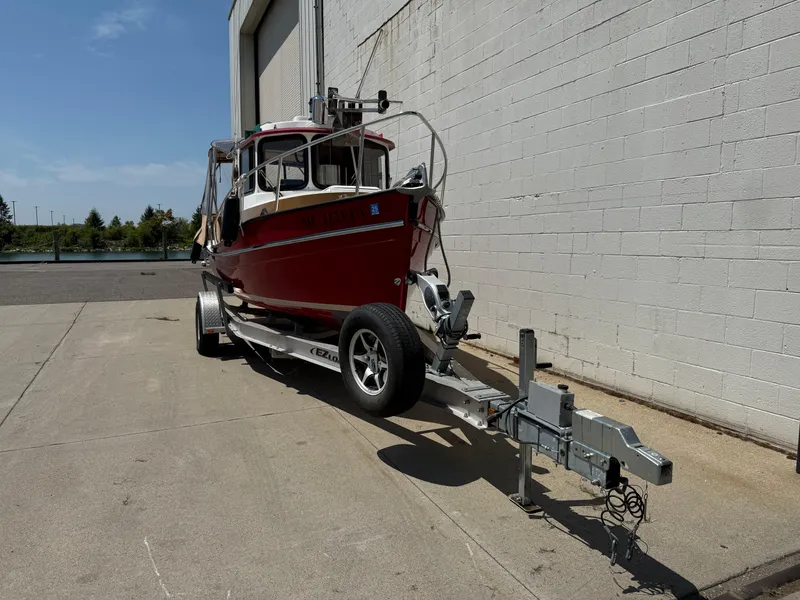Slide: The Image of 2016 Ranger Tugs R-21 EC boat on trailer, parked near a building. - 18