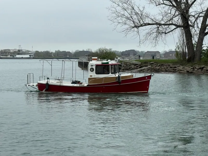Slide: The Image of 2016 Ranger Tugs R-21 EC boat on calm water near shoreline with trees. - 2