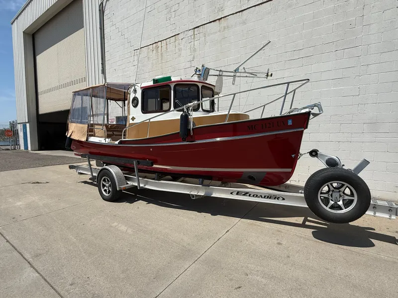Slide: The Image of 2016 Ranger Tugs R-21 EC boat on trailer, parked outside a large building. - 21