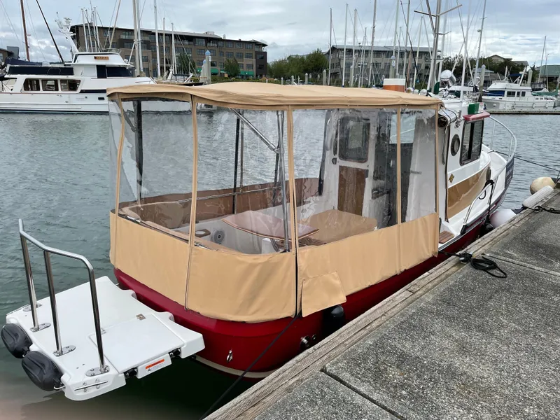 Slide: The Image of 2016 Ranger Tugs R-21 EC docked, featuring tan canopy and red hull in a marina setting. - 4