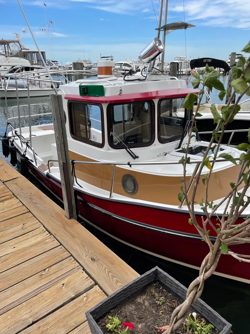 Slide: The Image of 2016 Ranger Tugs R-21 EC docked at marina, red and white exterior. - 5