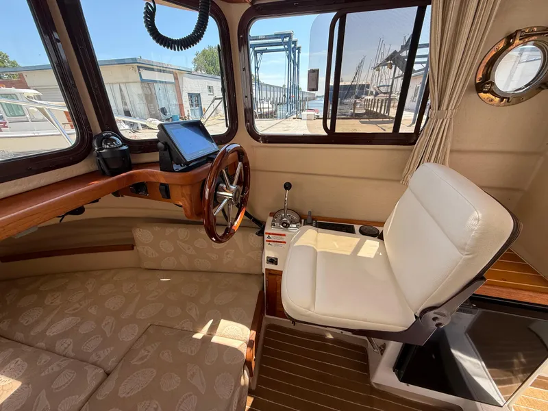 Slide: The Image of 2016 Ranger Tugs R-21 EC interior with helm, steering wheel, and cushioned seating. - 7