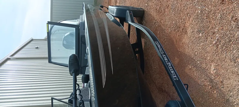 Slide: The Image of 2024 Ranger VX1888 WT boat on trailer, parked on gravel near a metal building. - 13