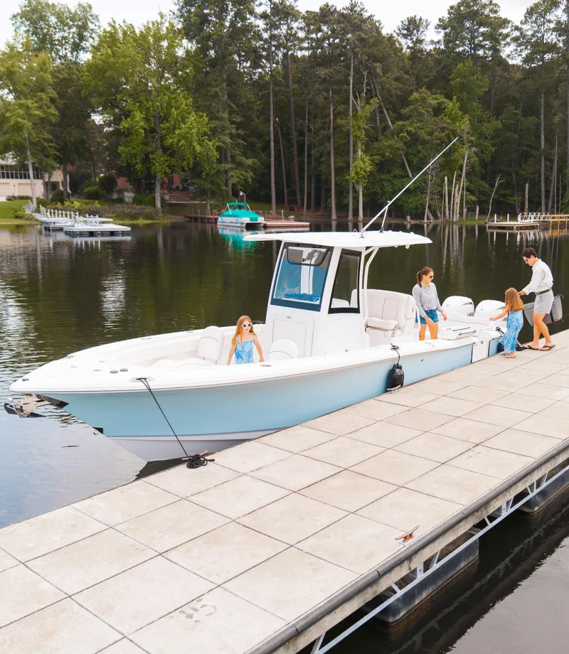 Slide: The Image of 2025 Sea Hunt Ultra 265 SE boat docked on a serene lake with people onboard. - 26