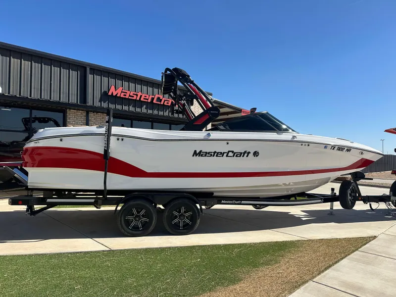 The Image of 2023 MasterCraft X26 boat with red and white design on a trailer. - 0