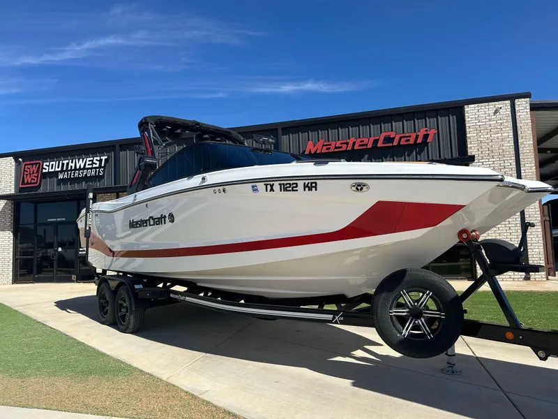 Slide: The Image of 2023 MasterCraft X26 boat on trailer outside Southwest Watersports dealership. - 2