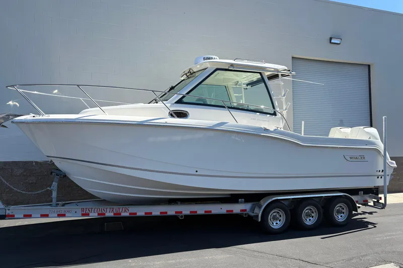 The Image of 2026 Boston Whaler 285 Conquest boat on trailer, parked outside a building. - 0