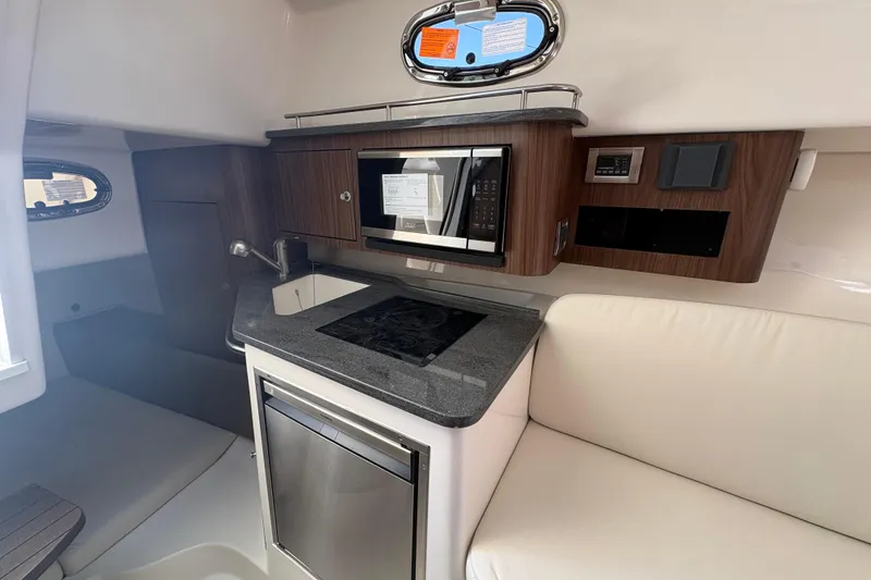 Slide: The Image of 2026 Boston Whaler 285 Conquest cabin interior with kitchenette and seating area. - 17