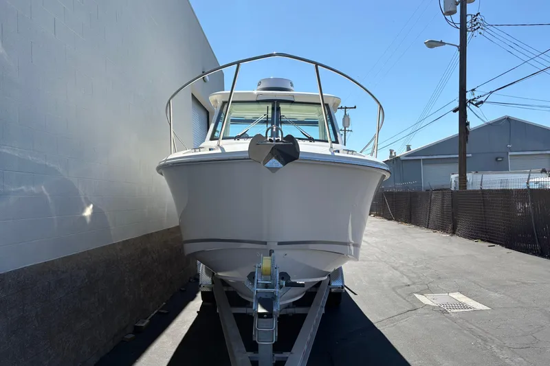 Slide: The Image of 2026 Boston Whaler 285 Conquest boat on trailer, parked in an industrial area. - 2