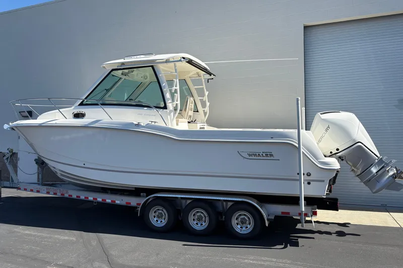Slide: The Image of 2026 Boston Whaler 285 Conquest boat on trailer, parked outdoors. - 3
