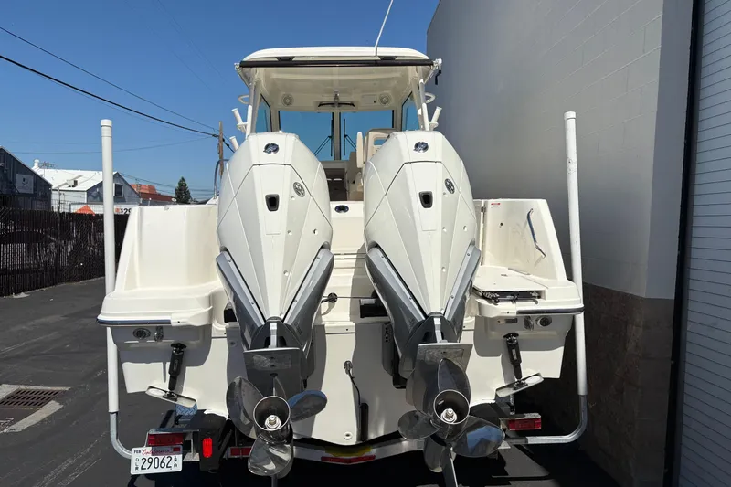 Slide: The Image of 2026 Boston Whaler 285 Conquest with dual outboard engines, rear view in a marina setting. - 5