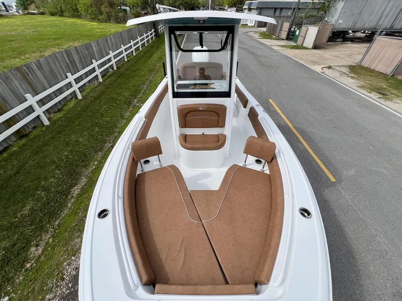 Slide: The Image of 2025 Sea Hunt Ultra 235SE boat with brown seating, docked on a paved road. - 16