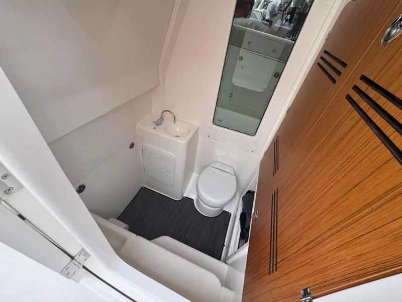 Slide: The Image of 2025 Solace 30 CS boat bathroom with sink, toilet, and wooden door. - 22