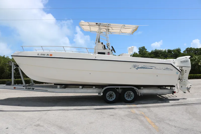 Slide: The Image of 1996 Sea Cat SL5 boat on trailer, white hull, Suzuki outboard motor, clear sky background. - 1