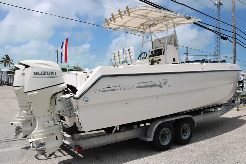 Slide: The Image of 1996 Sea Cat SL5 boat on trailer with Suzuki outboard motors, parked outdoors. - 3