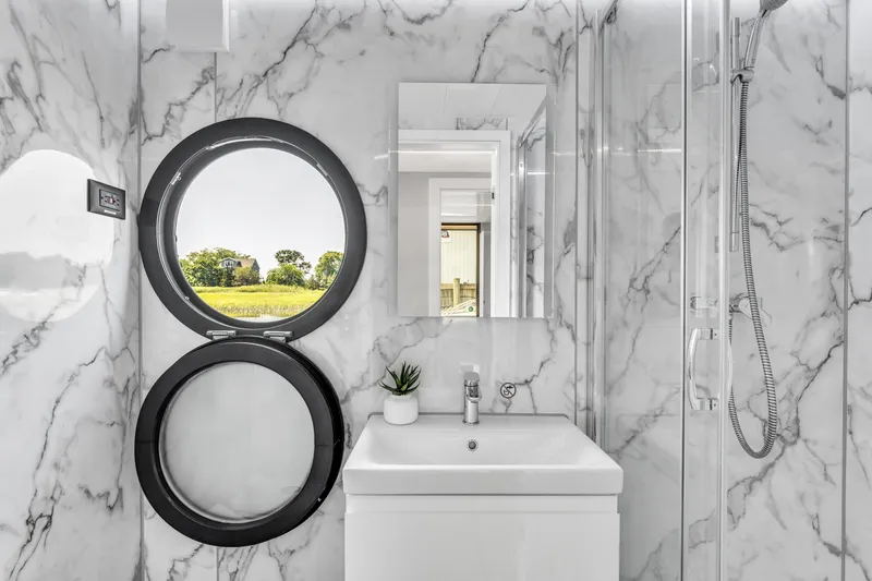 Slide: The Image of Modern bathroom in Waterlodge Apart XXL 2025, featuring marble walls and round window. - 22