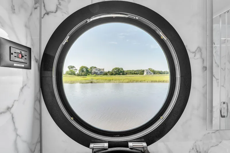 Slide: The Image of Porthole view from Waterlodge Apart XXL 2025, overlooking serene water and lush greenery. - 23