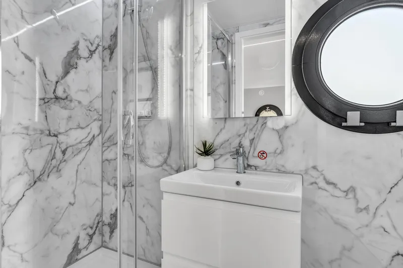 Slide: The Image of Modern bathroom in Waterlodge Apart XXL 2025, featuring marble walls and round window. - 32