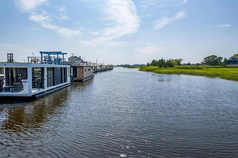 Slide: The Image of Houseboats on a serene river, featuring a 2025 Waterlodge Apart XXL model. - 43