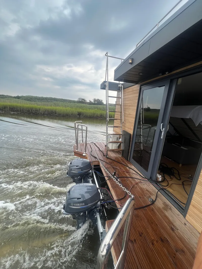 Slide: The Image of Modern Waterlodge Apart XXL houseboat cruising on a river, showcasing sleek design and dual outboard motors. - 46