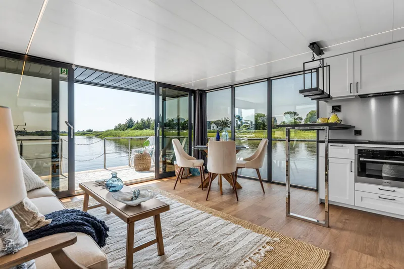 Slide: The Image of Modern Waterlodge Apart XXL 2025 interior with lake view, featuring cozy seating and dining area. - 9