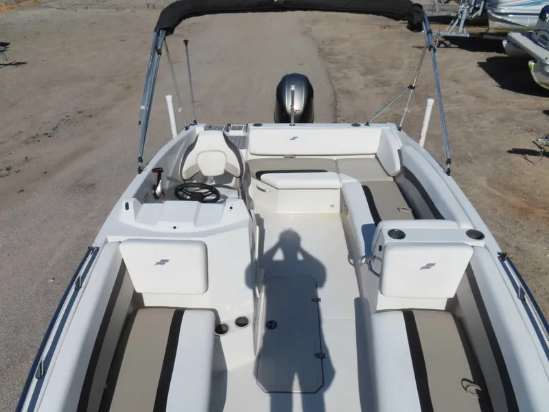 Slide: The Image of 2022 Starcraft SVX 171 boat interior with seating and steering wheel, parked on sandy ground. - 11