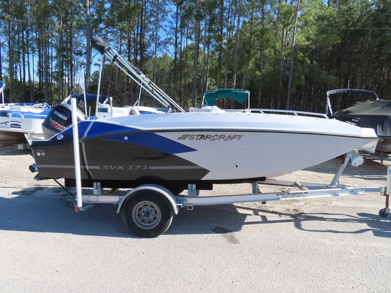 Slide: The Image of 2022 Starcraft SVX 171 boat on trailer, parked outdoors with trees in background. - 27