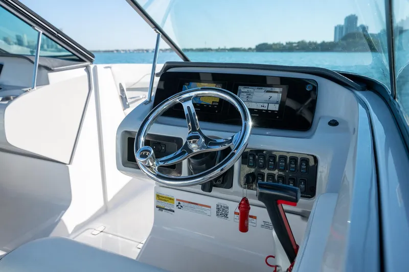 Slide: The Image of 2022 Regal LX2 boat helm with steering wheel and control panel, on a sunny day. - 13