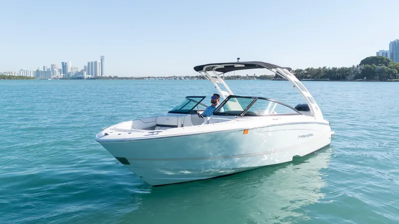 Slide: The Image of 2022 Regal LX2 boat cruising on clear blue water near a city skyline. - 6