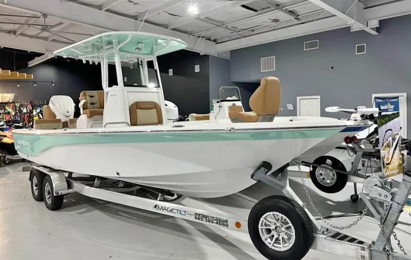 Slide: The Image of 2025 NauticStar 274 Bay boat on trailer in showroom, featuring sleek design and modern amenities. - 1
