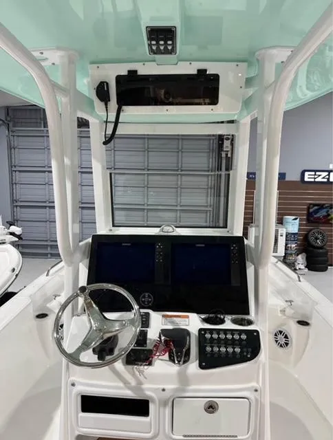 Slide: The Image of 2025 NauticStar 274 Bay boat console with dual screens and steering wheel in a garage setting. - 5