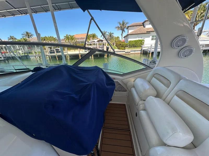 Slide: The Image of 2005 Sea Ray 320 Sundancer interior with white seating and marina view. - 15