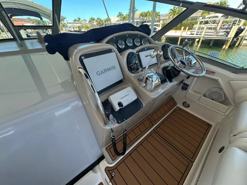 Slide: The Image of 2005 Sea Ray 320 Sundancer helm with Garmin navigation, luxurious interior, and waterfront view. - 18