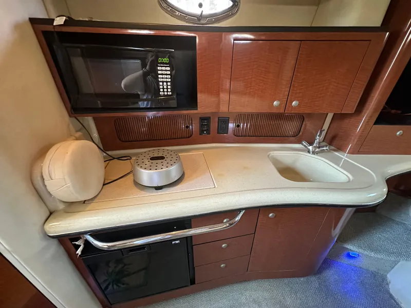 Slide: The Image of 2005 Sea Ray 320 Sundancer galley with microwave, sink, and storage cabinets. - 21