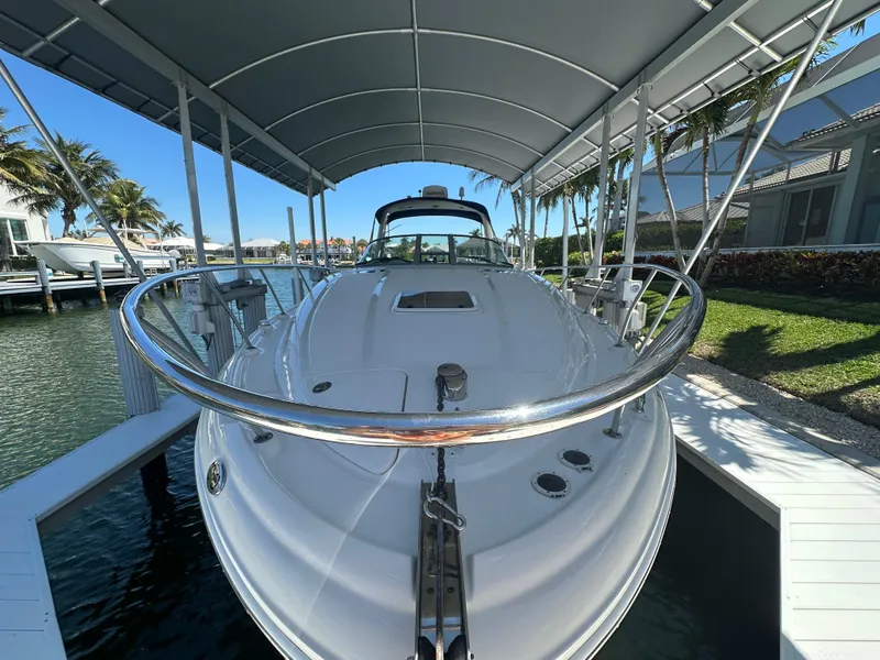 Slide: The Image of 2005 Sea Ray 320 Sundancer docked under a canopy, surrounded by water and palm trees. - 6