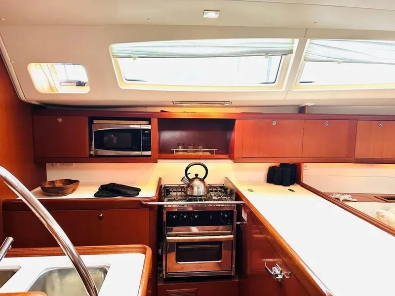 Slide: The Image of Interior of 2007 Beneteau 49' Cruiser kitchen with stove, microwave, and wooden cabinetry. - 17