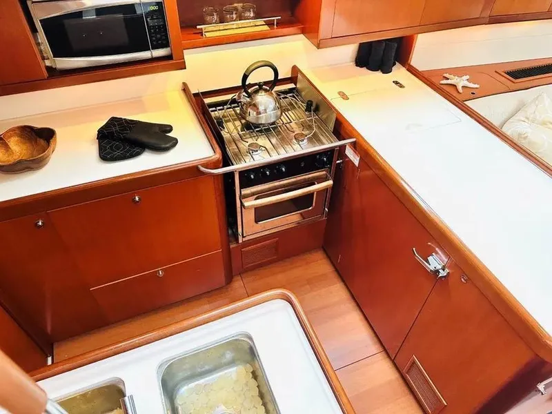 Slide: The Image of 2007 Beneteau 49' Cruiser kitchen with stove, oven, and wooden cabinetry. - 19