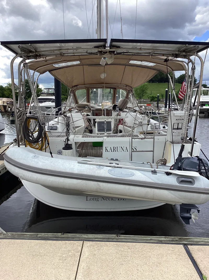 Slide: The Image of 2007 Beneteau 49' Cruiser docked, featuring a dinghy and covered cockpit. - 32